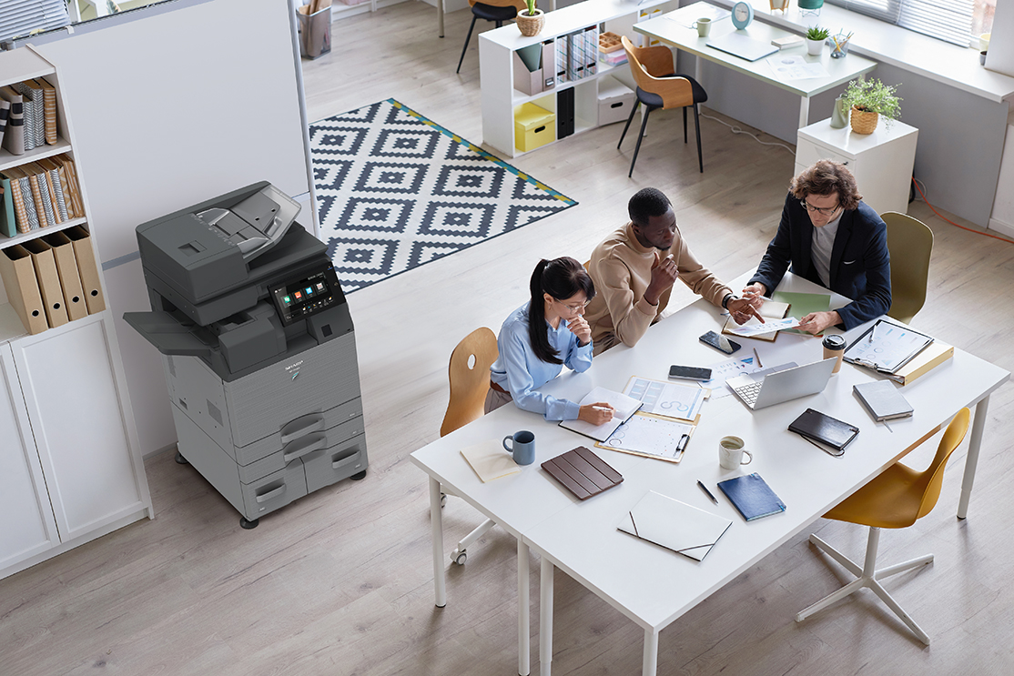 birds eye view of a printer in an office space with works collaborating around a table